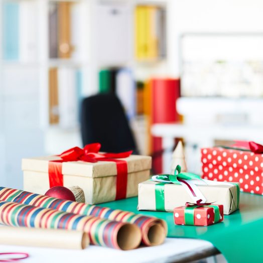 Group of packed gifts in boxes and rolled wrapping paper on table in studio